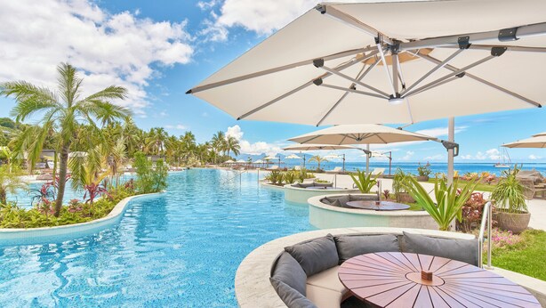 A poolside area with a curved seating area, umbrellas, and a view of the ocean. - Hilton Hotel Tahiti (Faaa)