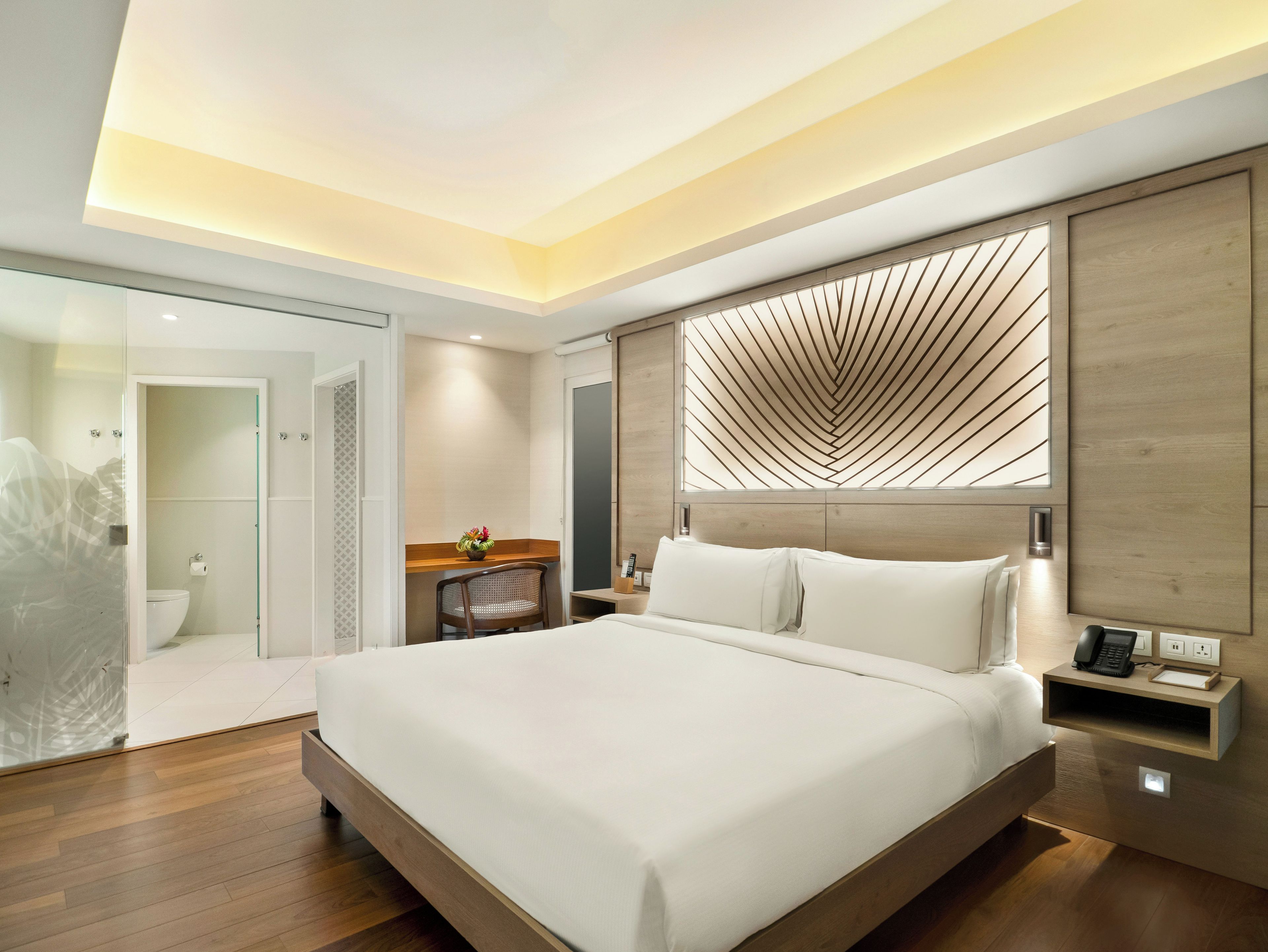 A modern hotel room with a large bed, a desk, and a shower area.