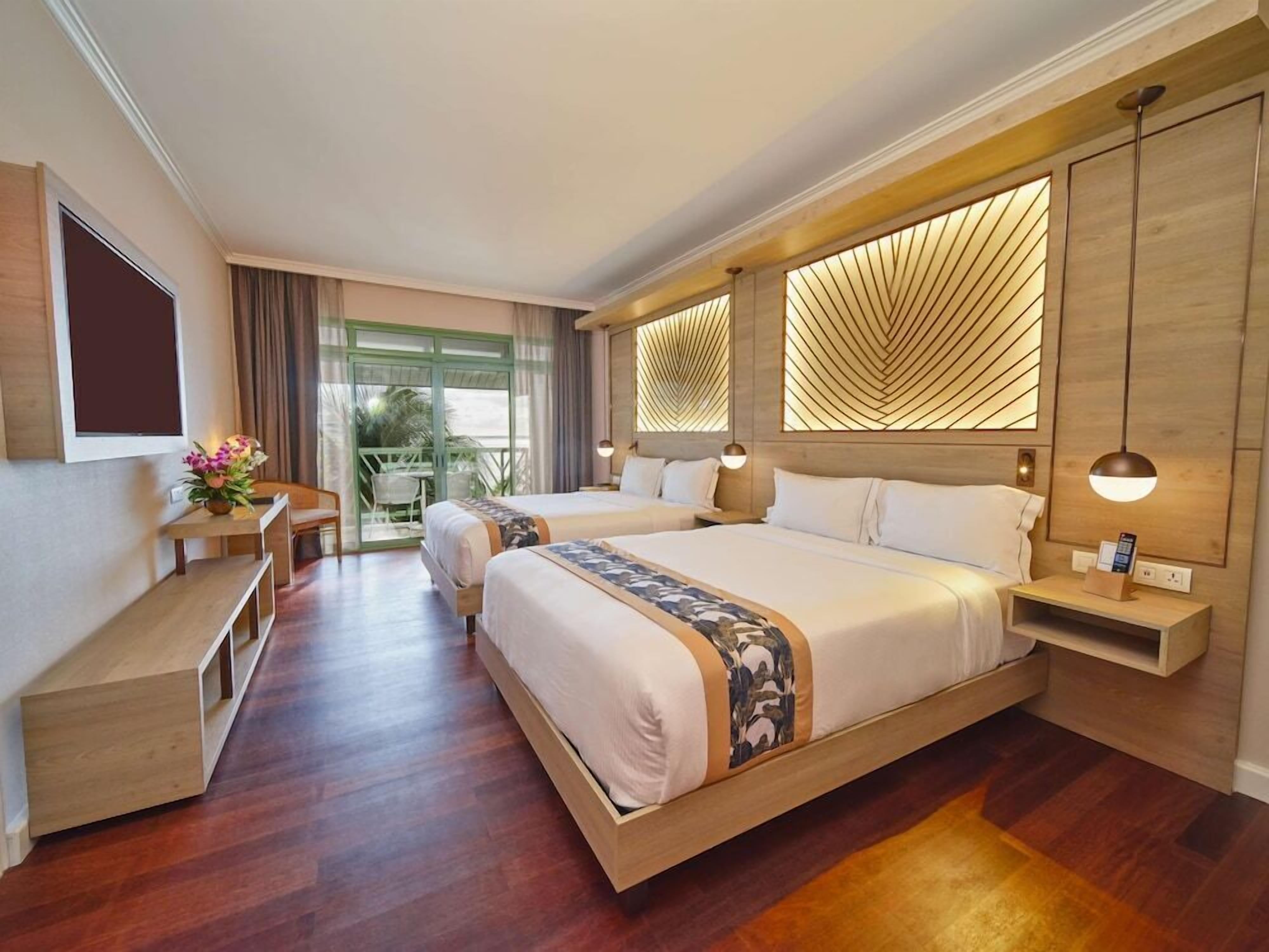 Ein modernes Hotelzimmer mit zwei Betten, einem Schreibtisch und einem Balkon.