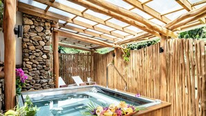 A hot tub with a wooden deck, a stone wall, and a wooden fence. - Hilton Hotel Tahiti (Faaa)