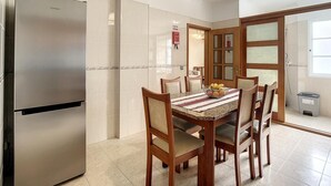 A modern kitchen with a stainless steel refrigerator, a dining table with chairs, and a window with a view. - Milagres Apartment by Atlantic Holiday (Machico)