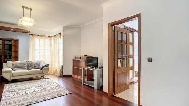 A living room with a sofa, a TV, a wooden cabinet, and a patterned rug. - Milagres Apartment by Atlantic Holiday (Machico)