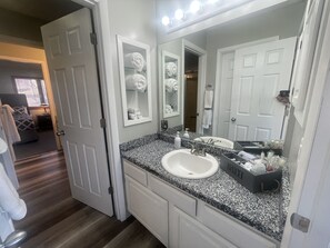 A bathroom with a white sink, a large mirror, and a vanity with a black countertop. - SO MUCH FUN! ARCADE, PL TBL, PNG PNG, YARD GAMES, INDOOR AND OUTDOOR POOLS!! (Des Moines)