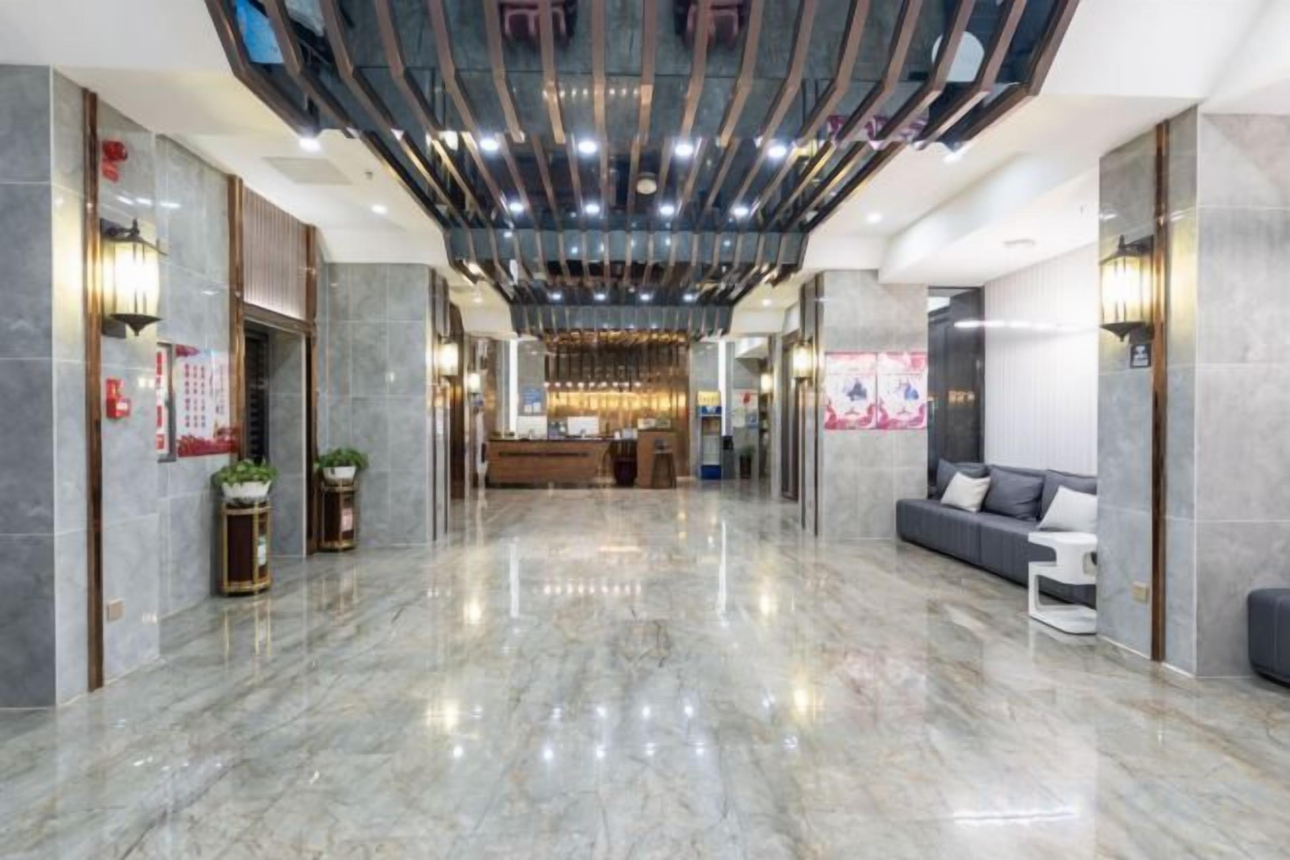 A hotel lobby with a marble floor, a reception desk, a sofa, and a chandelier.