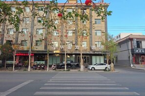 A hotel with a storefront, a crosswalk, and a parked car.