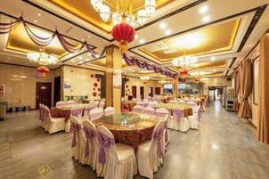 Un salón de banquetes con mesas redondas, sillas y candelabros.