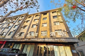 Um edifício de vários andares com a placa 'HUA SHENG BUSINESS HOTEL'.