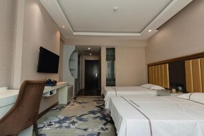Una habitación de hotel con cama, escritorio, silla, televisor y puerta del baño.