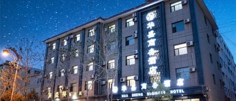 A multi-story hotel with illuminated signage, a visible entrance, and a clear view of the street.