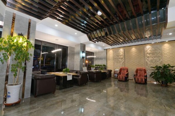 Eine moderne Lobby mit hoher Decke, Sitzgelegenheiten und dekorativen Wandverkleidungen.
