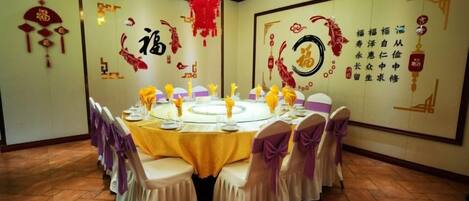 A round table with a yellow tablecloth and white chairs, surrounded by red decorations and Chinese characters on the walls.