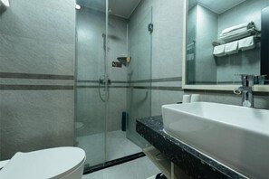 Ein modernes Badezimmer mit Duschkabine aus Glas, einem weißen Waschbecken und einem Spiegel darüber.