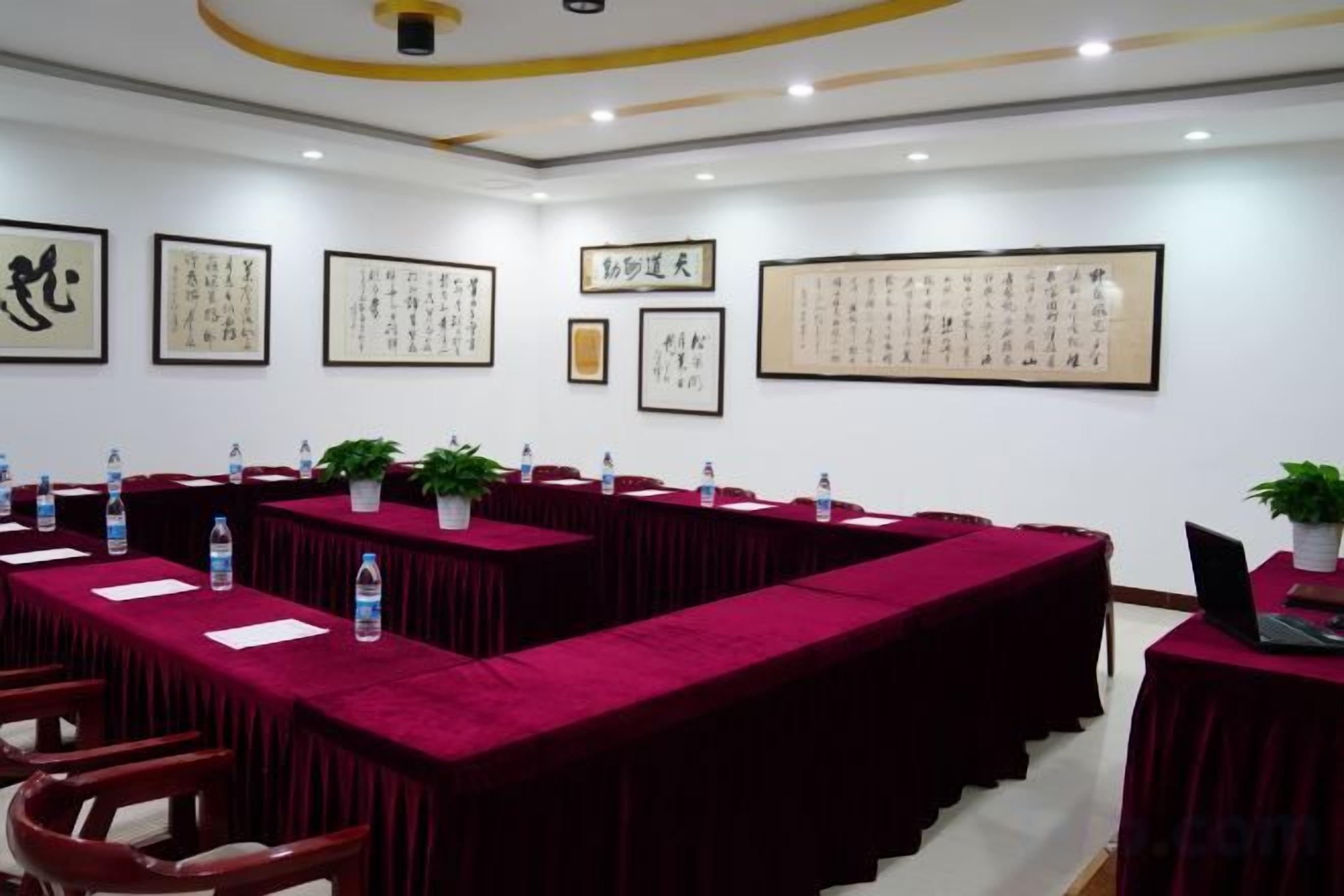 A conference room with long tables, chairs, and framed calligraphy on the walls.