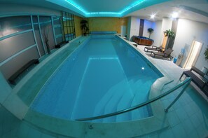 A large indoor swimming pool with a glass barrier, lounge chairs, and a water fountain. - Brotnjo (Citluk)