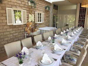 A long dining table set for a formal meal with white tablecloths, plates, and silverware. - Brotnjo (Citluk)