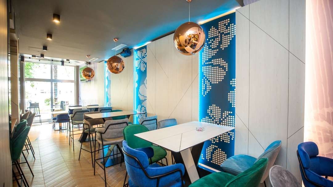 A modern interior with a dining area featuring tables and chairs, a large window, and decorative wall panels.
