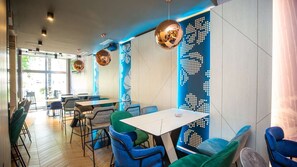 A modern interior with a dining area featuring tables and chairs, a large window, and decorative wall panels. - Brotnjo (Citluk)