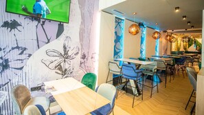 A restaurant interior with a modern design, featuring wooden tables and chairs, a large TV screen, and decorative wall art. - Brotnjo (Citluk)