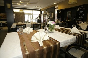 A restaurant interior with tables set for dining, featuring white tablecloths, folded napkins, and glassware. - Brotnjo (Citluk)