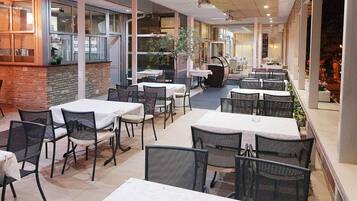 An indoor dining area with tables and chairs, a ceiling fan, and a view of the street outside.
