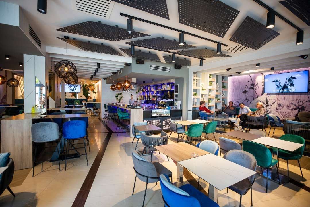 A modern restaurant with a bar area, seating, and a TV screen.