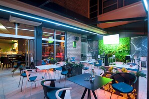 An outdoor dining area with tables and chairs, a brick wall, and a green wall with plants. - Brotnjo (Citluk)