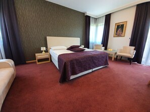 Una habitación de hotel con una cama grande, un escritorio, una silla y un sofá.
