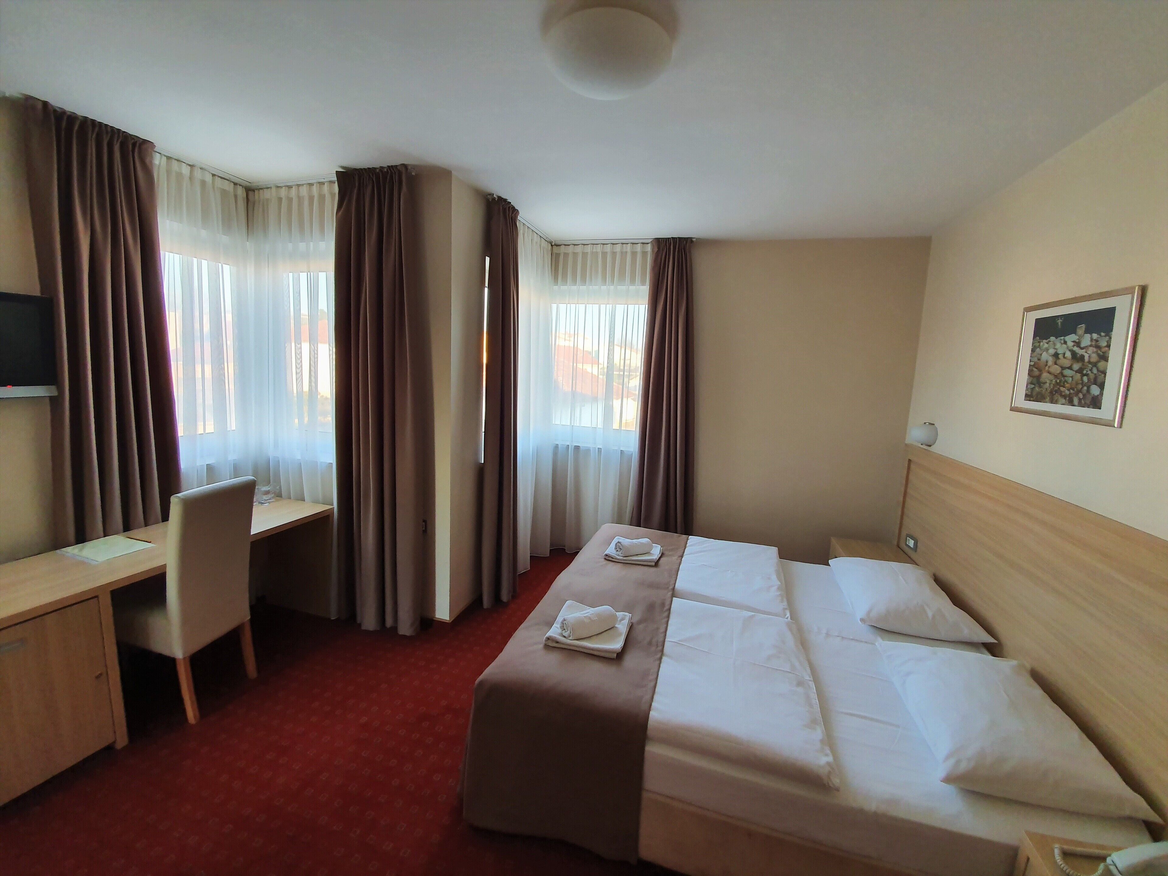 Une chambre d’hôtel équipée d’un lit, d’un bureau, d’une chaise et d’un téléviseur.