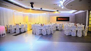 A banquet hall with round tables, white tablecloths, and chairs.