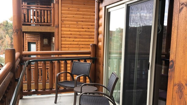 Une cabane en bois dotée d’un balcon avec deux chaises et une table.