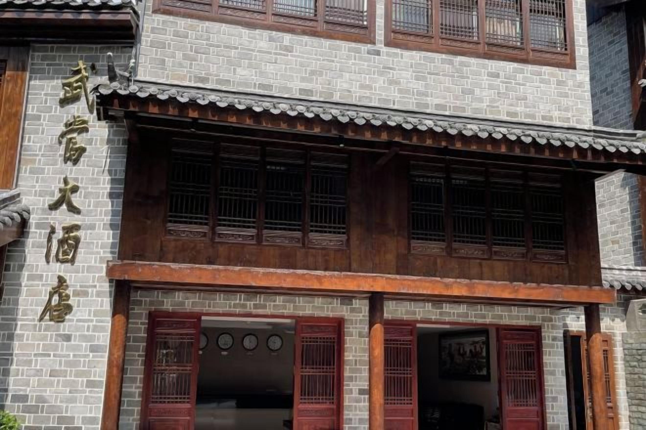 Edifici tradicional amb teulada de rajola, marc de finestres de fusta i façana de maó.