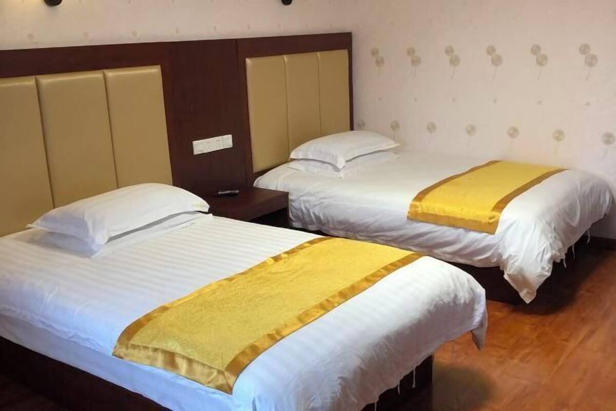 Two single beds with headboards, a wooden floor, and a wall with a floral pattern.