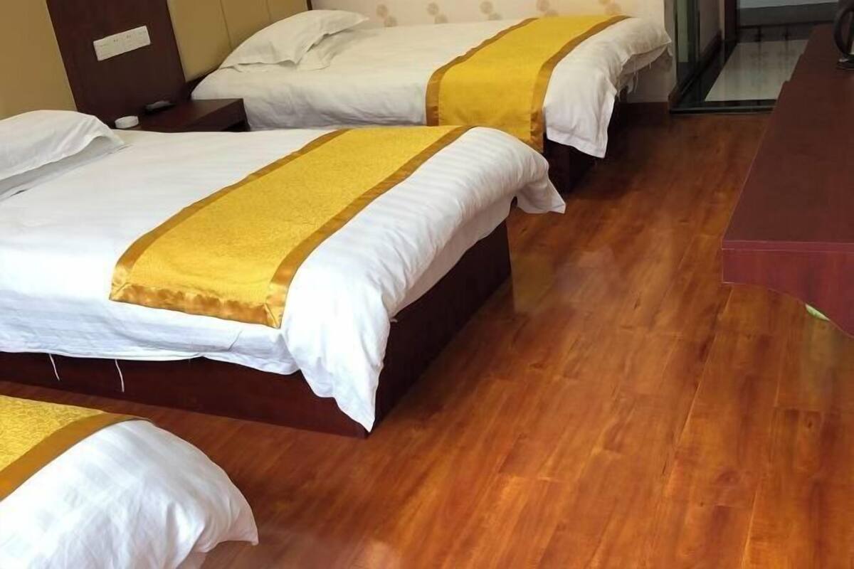 A hotel room with two beds, wooden flooring, and a small desk.