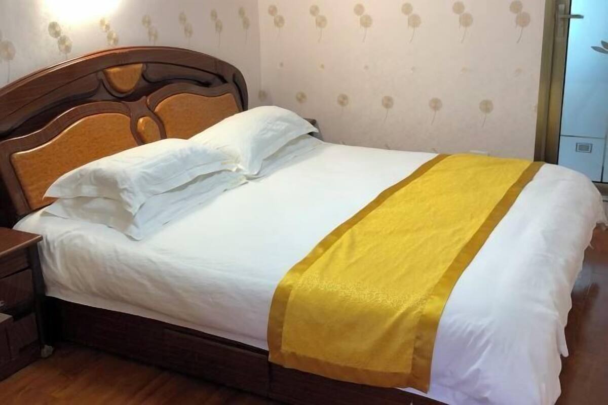 A neatly made bed with white bedding and a yellow accent.
