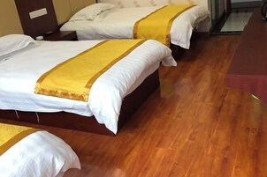 Quarto de hotel com duas camas, piso de madeira e uma pequena mesa.