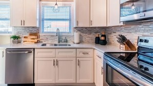A modern kitchen with light-colored cabinets, a stainless steel dishwasher, a double oven, and a window with blinds. - Great location, Close to everything in Bentonville (Bentonville)