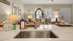 A kitchen with a stainless steel sink, a ceiling fan, and a window with blinds.