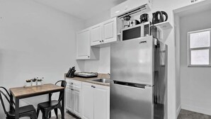 A compact kitchen with white cabinets, a stainless steel refrigerator, a microwave, and a coffee maker on the countertop. - Cozy Beach Studio | 1 Min to Hollywood Broadwalk (Hollywood)