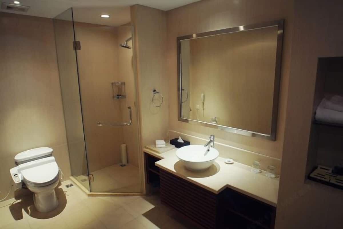 Ein modernes Badezimmer mit einer gläsernen Dusche, einem weißen Waschbecken und einem großen Spiegel.