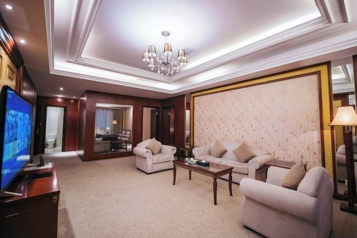 Ein geräumiges Wohnzimmer mit einem großen Flachbildfernseher, zwei Sofas, einem Couchtisch und einer Kristallleuchtre.