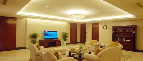 A modern living room with sofas, a coffee table, a TV, and a bookshelf.