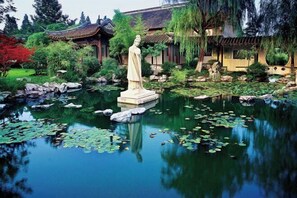 A serene garden with a statue, traditional architecture, and a pond with lily pads. - Taizhou Chunlan Guest House Old Street Branch (Taizhou)