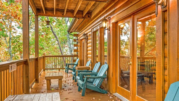 A wooden deck with Adirondack chairs and a table, surrounded by glass doors and windows. - Fall Break Special!•Hot Tub•Game Room•Sleeps 22•3600 sq ft •Pigeon Forge (Pigeon Forge)