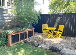 A garden area with a wooden planter, yellow chairs, and a black fence. - Crofty Cottage Dog-Approved Boise Bench Charmer with Private Fenced Yard (Boise)