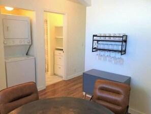 A compact living space with a laundry area, a dining table with chairs, and a wall-mounted glass storage unit. - Crofty Cottage Dog-Approved Boise Bench Charmer with Private Fenced Yard (Boise)