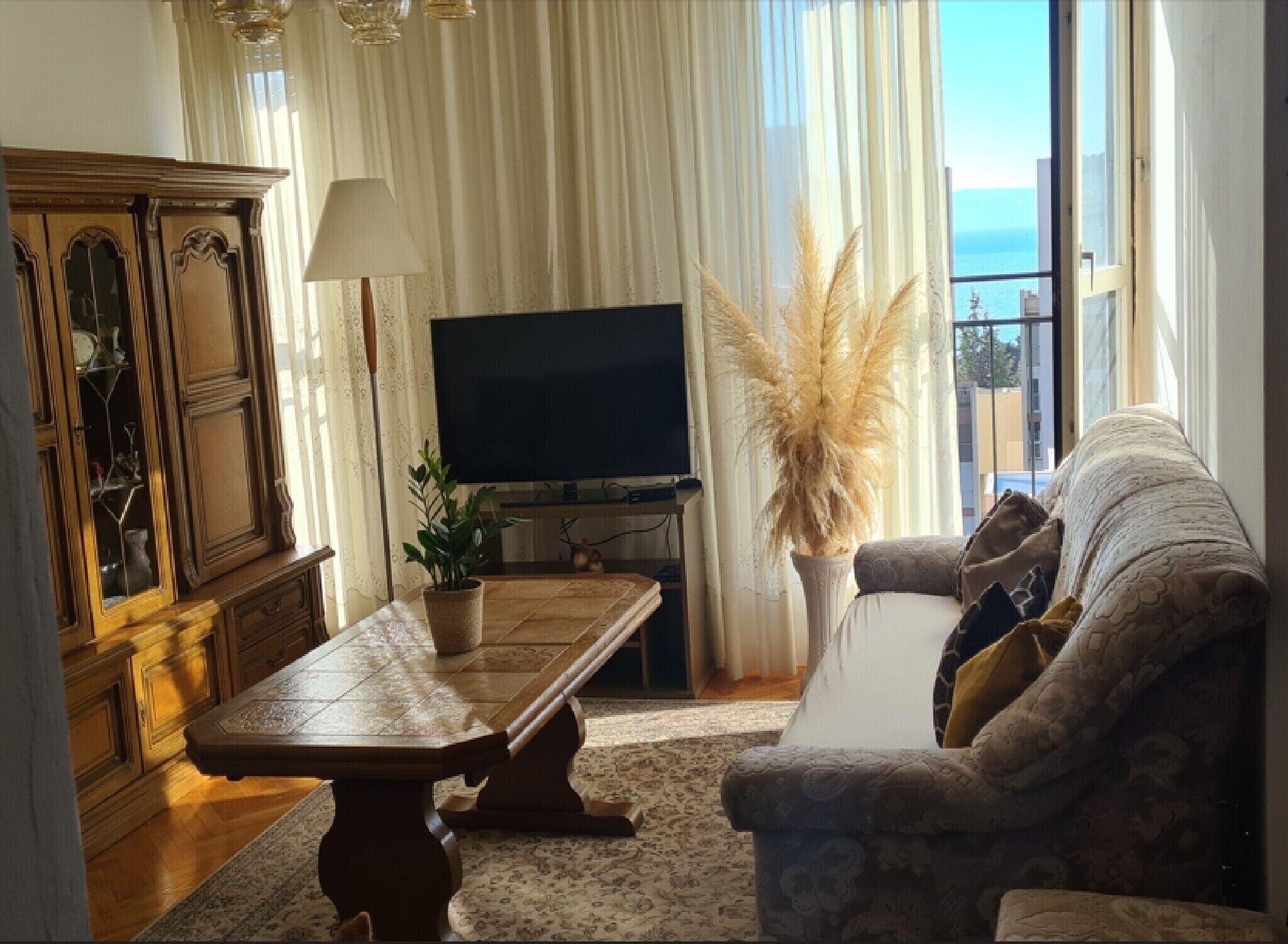 A living room with a sofa, a coffee table, a television, and a cabinet.