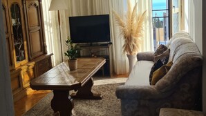 Olohuone, jossa on sohva, sohvapöytä, televisio ja kaappi.