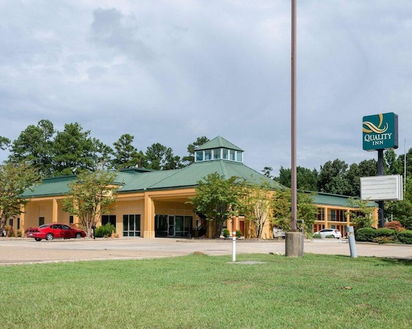 A hotel with a green roof, a signboard, and a red car parked in front. - Quality Inn Louisville MS (Louisville)