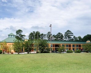 A building with a green roof, a tower-like structure, and a flat-roofed section. - Quality Inn Louisville MS (Louisville)
