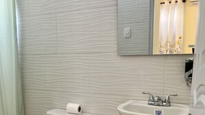 A bathroom with a toilet, a sink, and a mirror. - Hotel María Bonita Higüey,  room 301 Family property centrally located (Higüey)